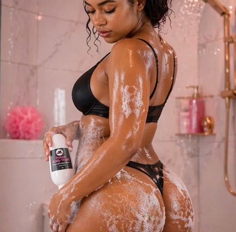 Woman in a black bikini holding a bottle of body wash with soap suds on her body in a bathroom.