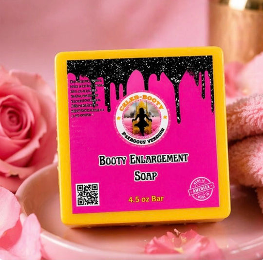 Soap bar with pink label and yellow border on a pink background with roses and bath bombs.