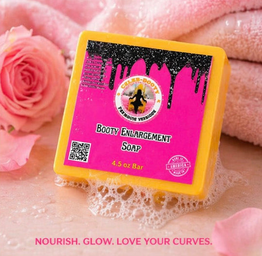 Bar of soap with pink label and yellow border on a textured surface with pink roses and fabric.